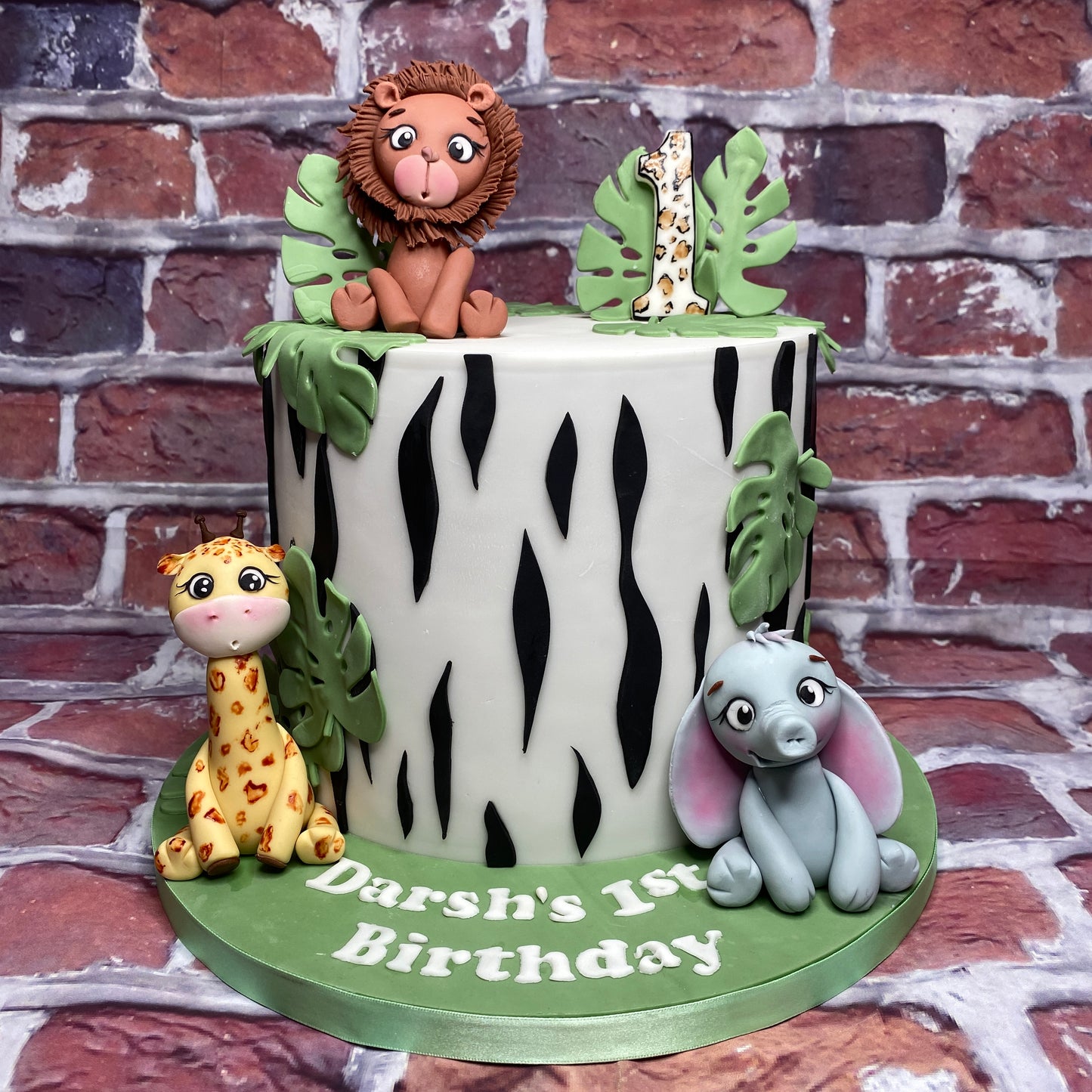 Birthday cake with animal figurines against a brick wall background