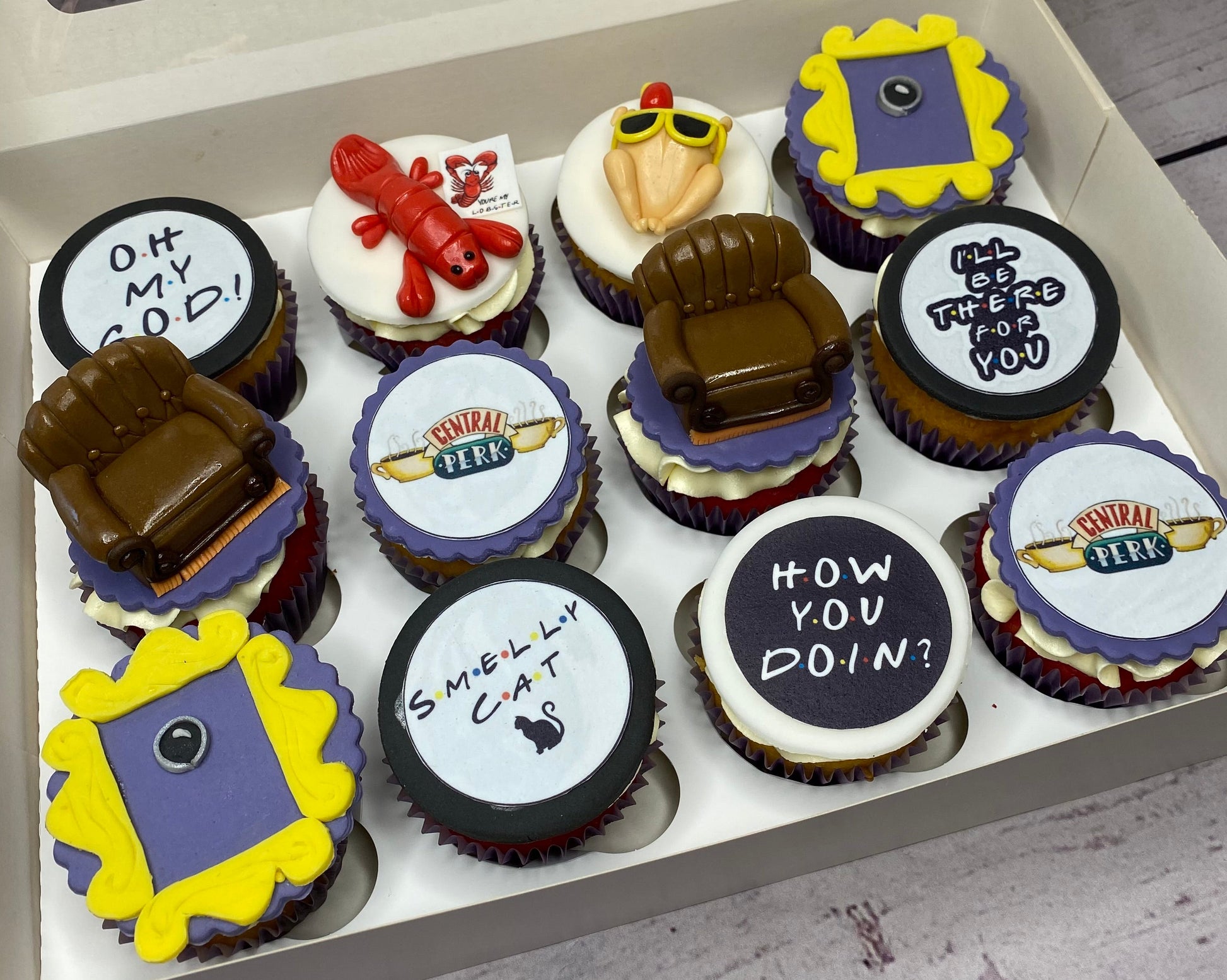 Box of cupcakes with FRIENDS TV Show-themed decorations 
