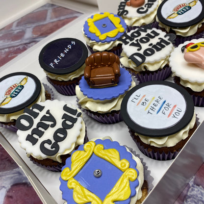 Cupcakes with decorative toppers featuring 'Friends' theme elements.