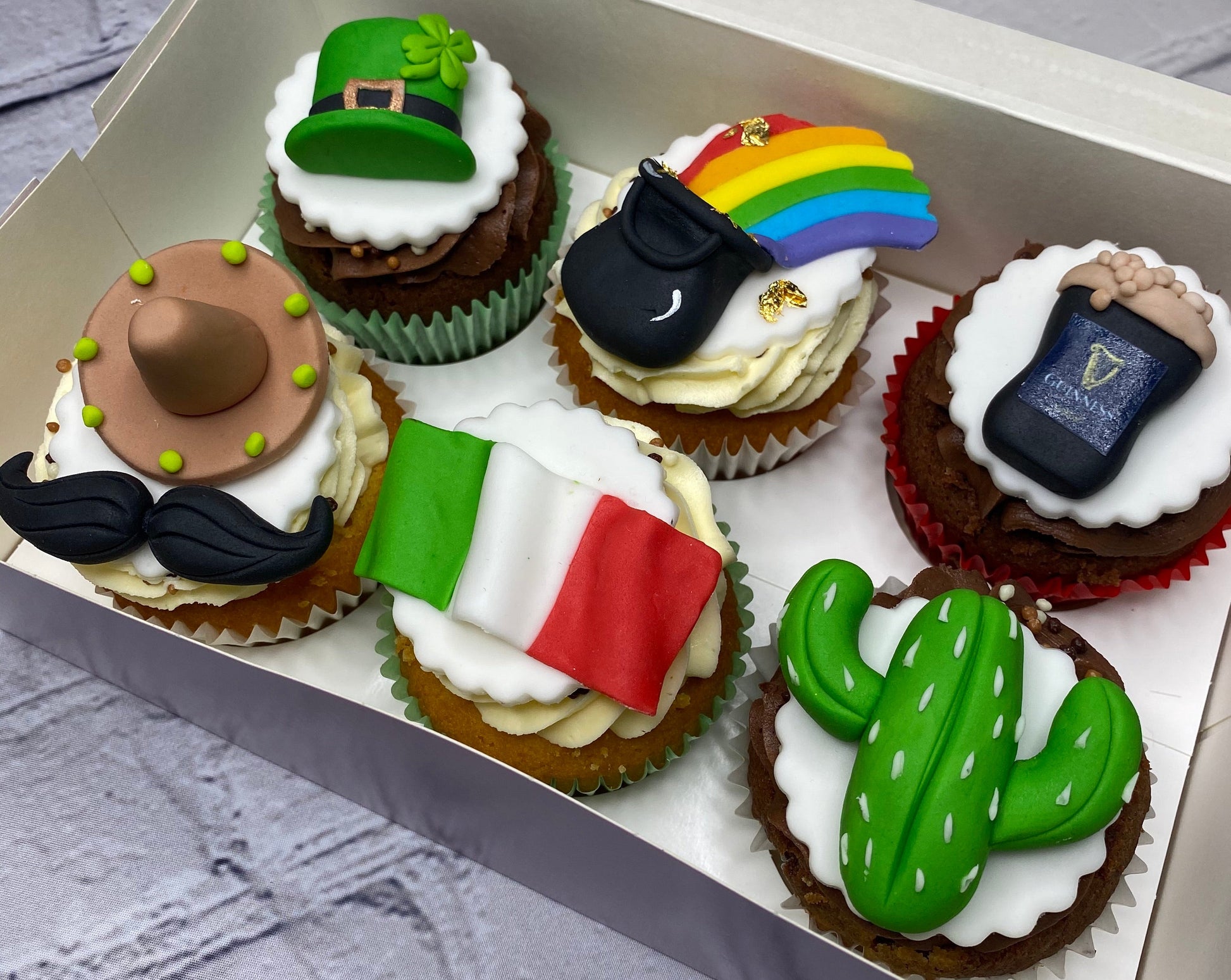 Decorative cupcakes with various themed toppings in a box.