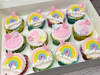 Box of cupcakes with rainbow and birthday-themed decorations 